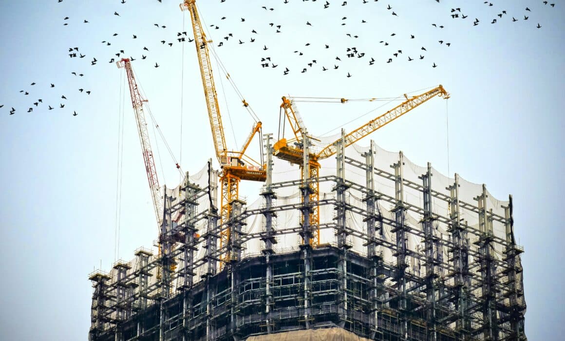 Construction image with cranes on the top of the building