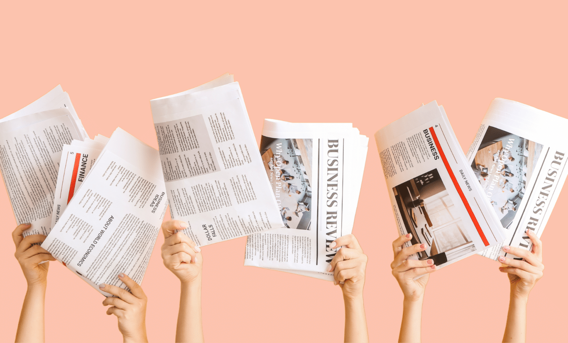 Image of hands holding trade press newspapers with a pink background